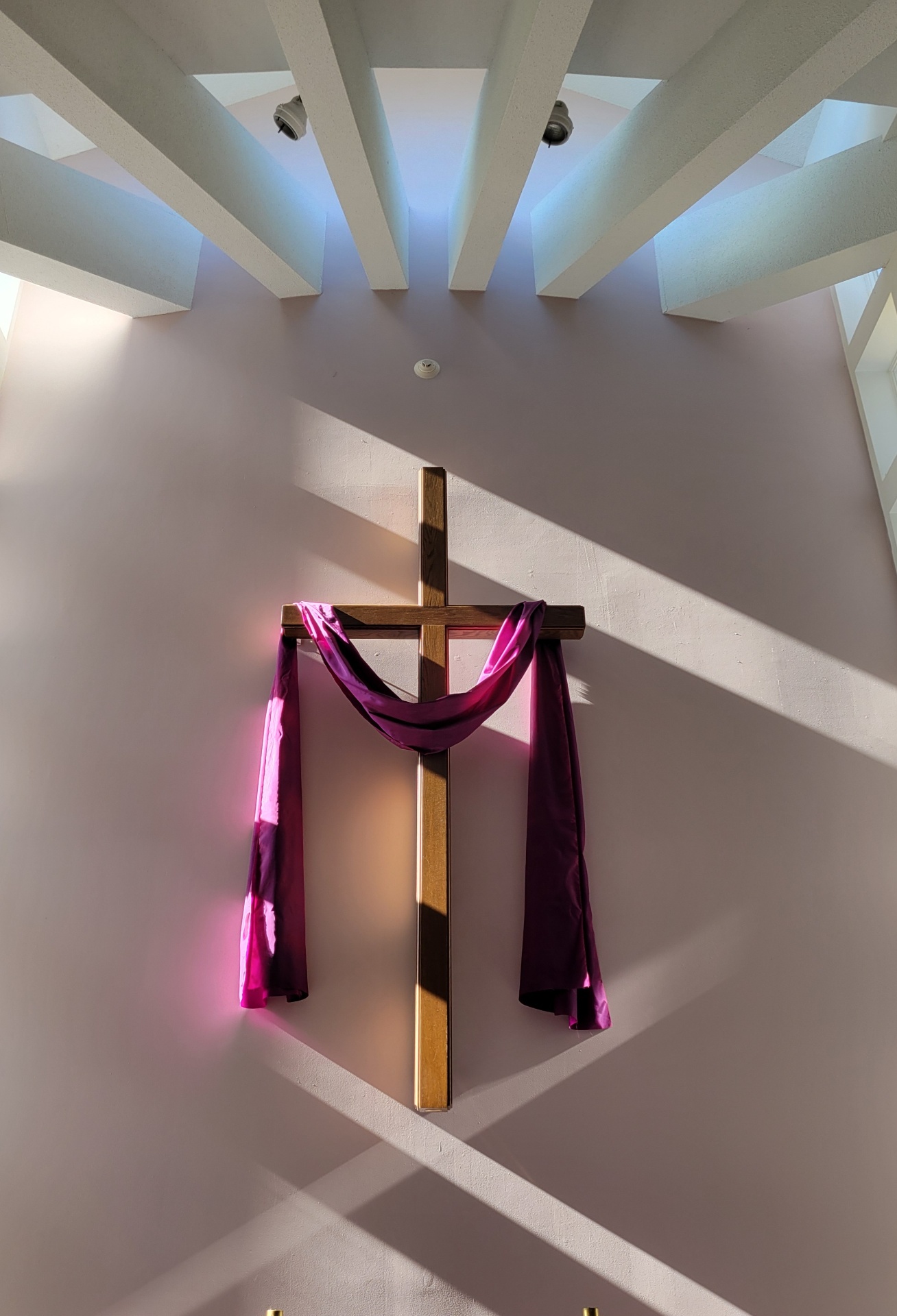 Sanctuary cross draped with a purple cloth, lit from the skylight above